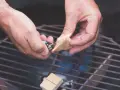 Hände zünden Grillanzünder an, um den Grill anzufeuern.