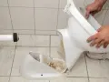 Démontage d'une cuvette de toilettes cassée. Il est temps de changer les toilettes.