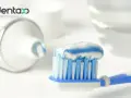Niebiesko-biała pasta do zębów na szczoteczce, obok tubki. Wybierz bezpieczne pasty do zębów dla zdrowego uśmiechu.