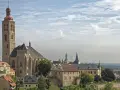 Majestatyczna katedra i zabytkowe budynki w Kutnej Horze pod błękitnym, chmurnym niebem.