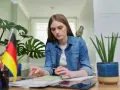 Dziewczyna z papugą na ramieniu uczy się niemieckiego. Może szuka inspiracji na piosenkę na urodziny po niemiecku?