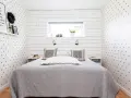 Ideen für ein sehr kleines Schlafzimmer einrichten: Sternen-Tapete, schlichtes Bett, Nachttische und ein Regal mit Deko.