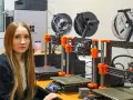 Kobieta w laboratorium obok rzędu drukarek 3D, które są kluczowe dla historii drukarki 3d.