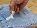 Mano quitando chicle pegado en bolsillo de jeans. Aprende como quitar chicle de la ropa fácilmente.