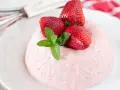 Deliziosa bavarese alle fragole, guarnita con fragole fresche e menta, su un piatto bianco.