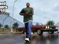 CJ camina con un arma, listo para usar trucos San Andreas PS2. Un coche clásico rojo espera.