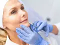 Mujer recibe tratamiento facial con exosomas. Manos enguantadas aplican inyección para rejuvenecer la piel.