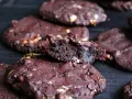 Schokoladenkekse mit Nüssen, die an das subway cookies rezept erinnern. Ein Keks ist zerbrochen und zeigt die saftige Innenseite.