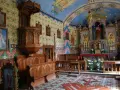 Wnętrze kościoła w Bukowinie Tatrzańskiej. Drewniana ambona, ławy i ołtarz zdobią kolorowe malowidła.