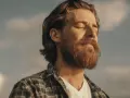 Homme à la barbe rousse, yeux fermés, profitant du soleil. Une image qui évoque le bien-être et la vitalité, peut-être liée à un test libido homme.