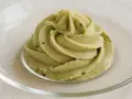 Puszysty krem pistacjowy do tortu, udekorowany na talerzyku.