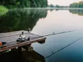 Wczesny poranek na Mazurach, mgła unosi się nad jeziorem, a wędka czeka na pierwszy brzeg. Idealne miejsce na wędkowanie na Mazurach.