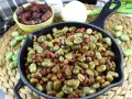 Habas tiernas salteadas con trocitos de jamón en una sartén de hierro fundido, un plato tradicional lleno de sabor.