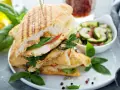 Pyszne panini z kurczakiem, pomidorem i bazylią, podane z sałatką z ogórka. Idealne na lekki posiłek.