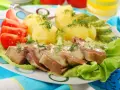 Pokrojone ozory wieprzowe w sosie, podane z ziemniakami, pomidorami i ogórkiem kiszonym.