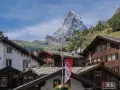 Tradycyjna winieta szwajcaria: drewniane domy z kamiennymi dachami i majestatyczny Matterhorn w tle.