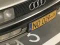 Zbliżenie na przednią część samochodu z żółtą tablicą rejestracyjną "NO 029" i logo Audi.