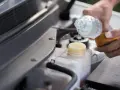 Mani versano acqua nel serbatoio del liquido di raffreddamento dell'auto, assicurandosi che ci sia acqua nel radiatore.