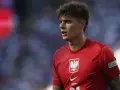 Młody piłkarz w czerwonej koszulce z orłem, symbolizujący polską reprezentację. Jego wzrost i determinacja na boisku budzą nadzieję na przyszłe sukcesy.