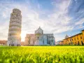 Torre di Pisa e Duomo, tra i più bei posti da visitare in Toscana, con un prato verde brillante e cielo azzurro.