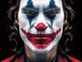 Intensywny joker makijaż z niebieskimi łzami i czerwoną, uśmiechniętą twarzą.