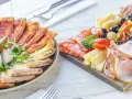 Talerz z pizzą i deska serów z wędlinami, oliwkami i pomidorkami.