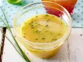 Ein Glas mit cremigem honig senf dressing, garniert mit Schnittlauch. Perfekt für einen frischen Salat.