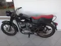 Czarny motocykl wsk 125 z czerwoną kanapą, stojący na szarej podłodze.
