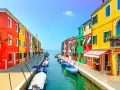 Coloratissima isola a Venezia, con case vivaci affacciate su un canale pieno di barche.