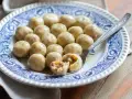 Gnocchi di pane saporiti, serviti su un piatto decorato. Uno è tagliato a metà, rivelando un ripieno gustoso.