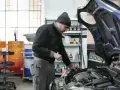 Mechanik w czapce z daszkiem sprawdza silnik. Zastanawiasz się, ile zarabia mechanik? Praca wymaga precyzji i wiedzy.