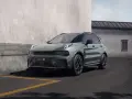 Nowoczesny, zielony SUV Lynk & Co 01 zaparkowany przy betonowej ścianie.