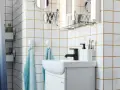 Salle de bain moderne avec carrelage blanc et joints dorés, évier, robinetterie noire et accessoires. Idéal pour un plancher chauffant avec un joint de 2mm.