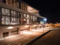 Nowoczesny budynek lotniska w nocy, z oświetlonymi oknami i pustymi drogami. Wygląda jak marbella lotnisko.
