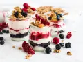 Leckeres Dessert mit Beeren und Joghurt in Gläsern geschichtet, garniert mit Granola und frischen Früchten.