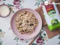 Arroz meloso con berenjenas en plato rosa, acompañado de queso rallado y bolsa de arroz Sabroz.