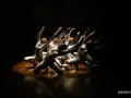 Un groupe de danseurs en costumes argentés, mains levées, dans un photo spectacle captivant.