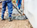 Pracownicy wylewają beton na zbrojenie. Sprawdź aktualny suchy beton cena 1m3.