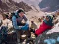 Uśmiechnięci alpiniści podczas wyprawy na Toubkal. W tle skaliste zbocza górskie.