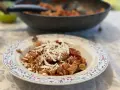 Plato de pasta alla norma con fusilli, berenjena, tomate y queso rallado, listo para disfrutar.