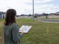 Kobieta z mapą w ręku dokonuje analizy działki w nowym osiedlu.