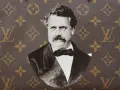 Ritratto in bianco e nero di Louis Vuitton, con il suo iconico monogramma sullo sfondo.