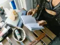 Kobieta czyta książkę, obok kryształy, szałwia i talizmany. Liczba 27 znaczenie w ezoteryce.
