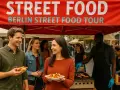 Glückliche Menschen genießen Hotdogs und Pommes auf einem Street Food Festival in Berlin.
