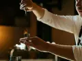 Barman nalewa ciemny płyn do jiggera, przygotowując drinka z Jägermeisterem i sokiem pomarańczowym.