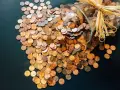 Góra monet rozsypana z słoika, symbolizująca oszczędności i potencjalne odsetki maksymalne.