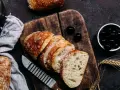 Frisches Brot, aufgeschnitten auf einem Holzbrett, daneben Oliven. Perfekt für den Gasgrill bei richtiger Temperatur.