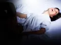 Kobieta w białej koszuli śmieje się, leżąc w łóżku. Jej ciało wygina się w zmysłowym geście, sugerując intymne chwile.