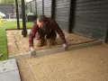 Man jämnar ut grus för att lägga plattor runt huset.