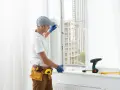 Un technicien installe une fenêtre à double vitrage. Outils et perceuse sur le rebord de la fenêtre.